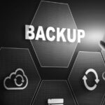 A hand points toward a glowing hexagon labeled BACKUP on a digital interface, surrounded by icons representing cloud storage, data synchronization, and files—perfect for illustrating a reliable backup or data recovery guide.