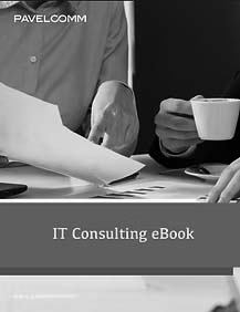 Two people sit at a desk reviewing papers and charts, with one person holding a cup of coffee. The text on the image reads IT Consulting eBook, PAVELCOMM, and highlights Virtual CIO Services for strategic business growth.